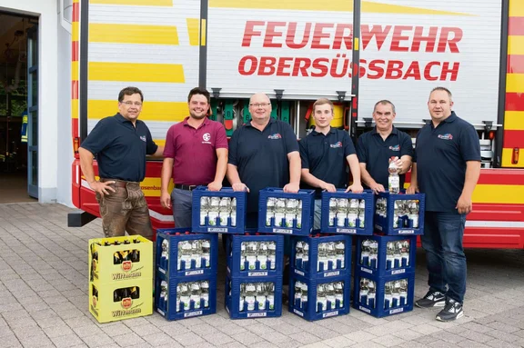 Personen mit Wasserkisten vor Feuerwehrauto