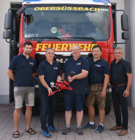 Personen vor Feuerwehrauto mit Wasserwerfer