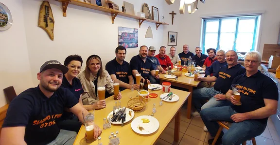Gruppe von Personen sitzt bei Weißwurstprobe in der Feuerwehrküche